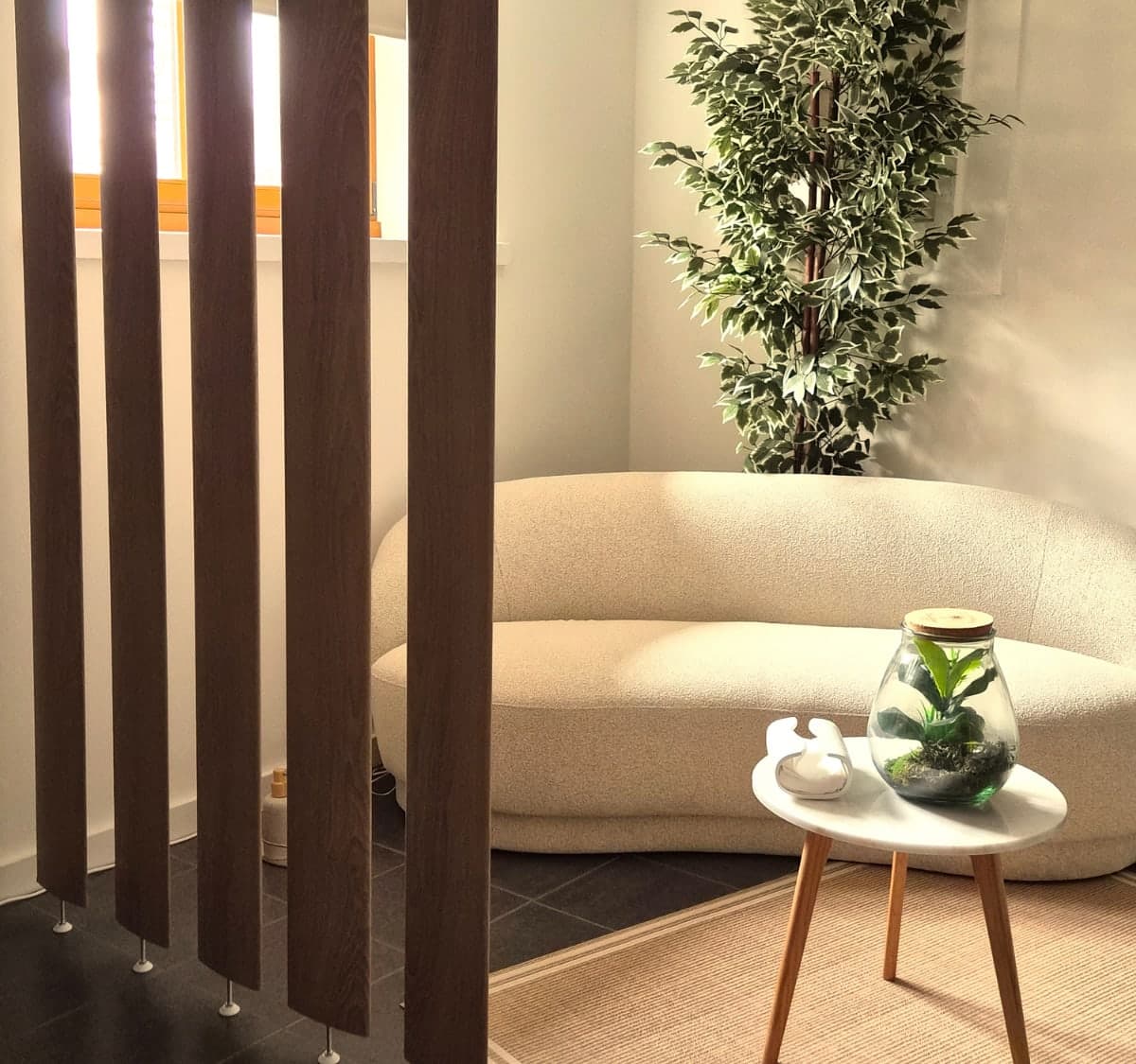 Le coin salon du cabinet avec son canapé bouclé et ses plantes
