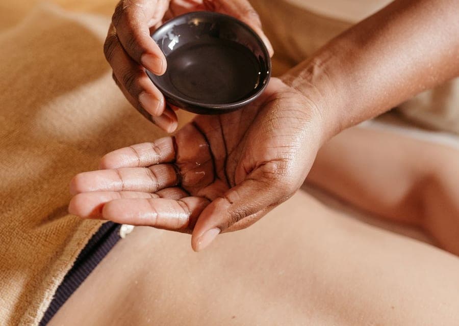 Huile chaude versée depuis un bol avant un massage du dos